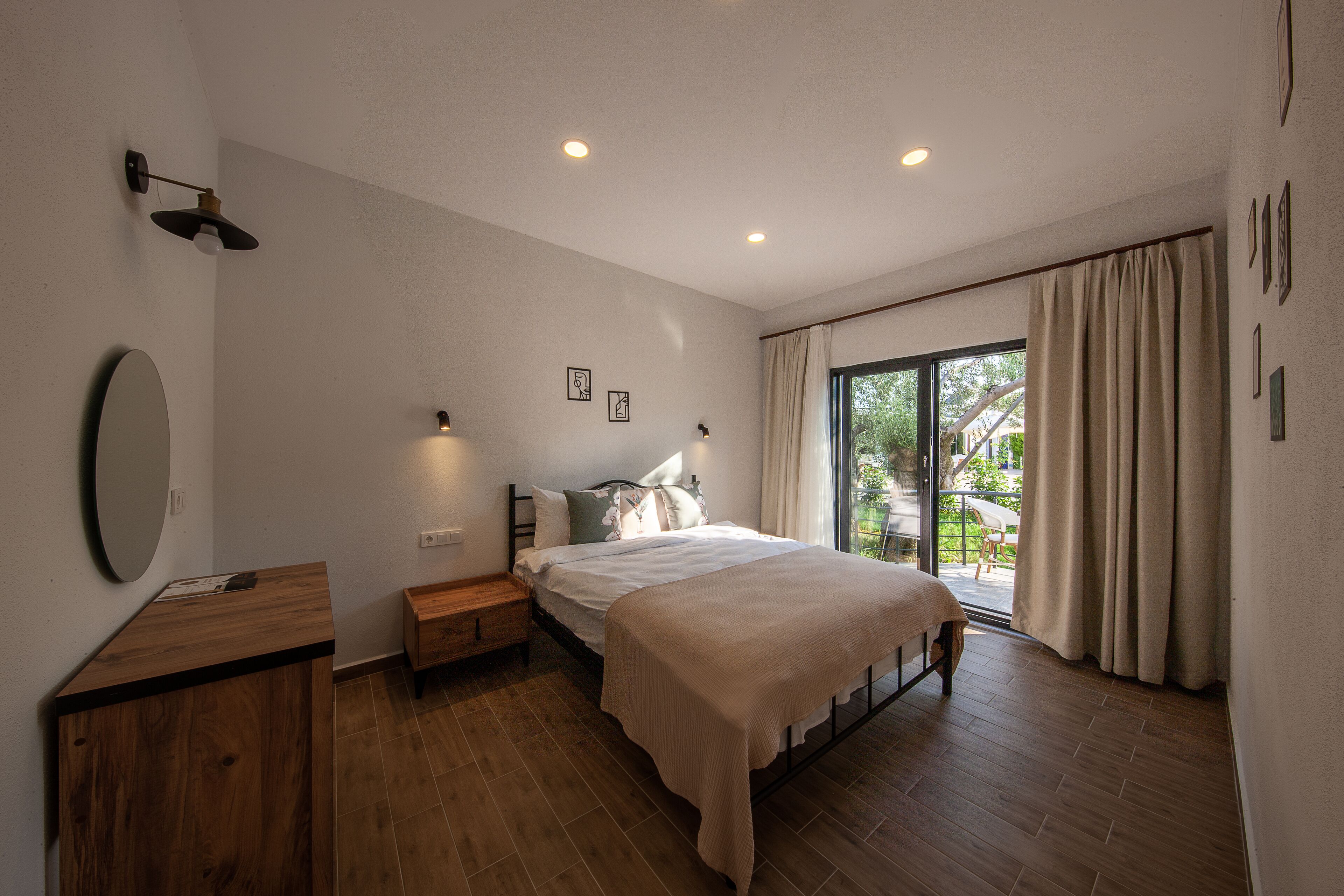 Un dormitorio con una cama grande, una mesita de noche, un espejo y una ventana con cortinas.