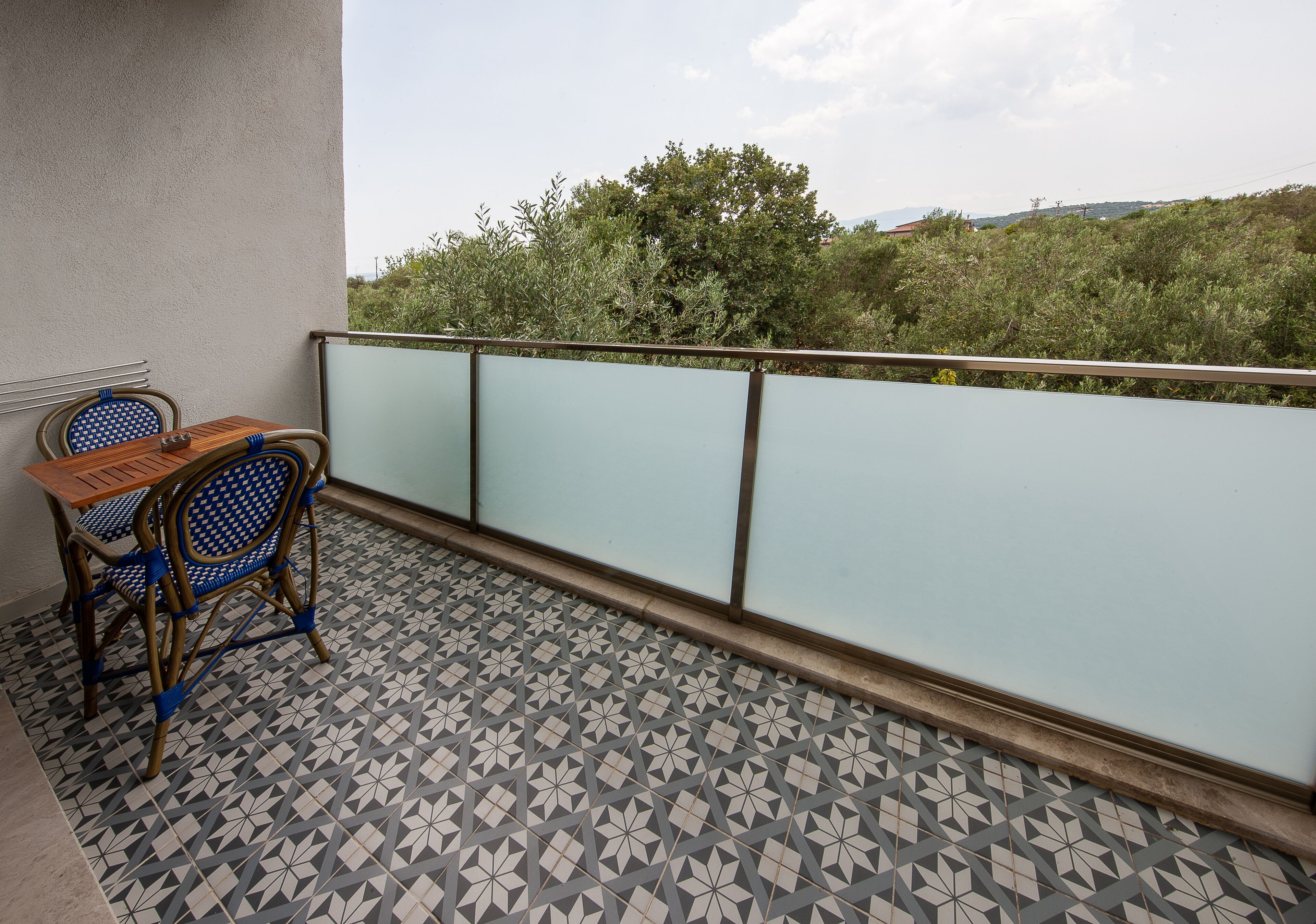 A balcony with a patterned floor, a table, and two chairs.