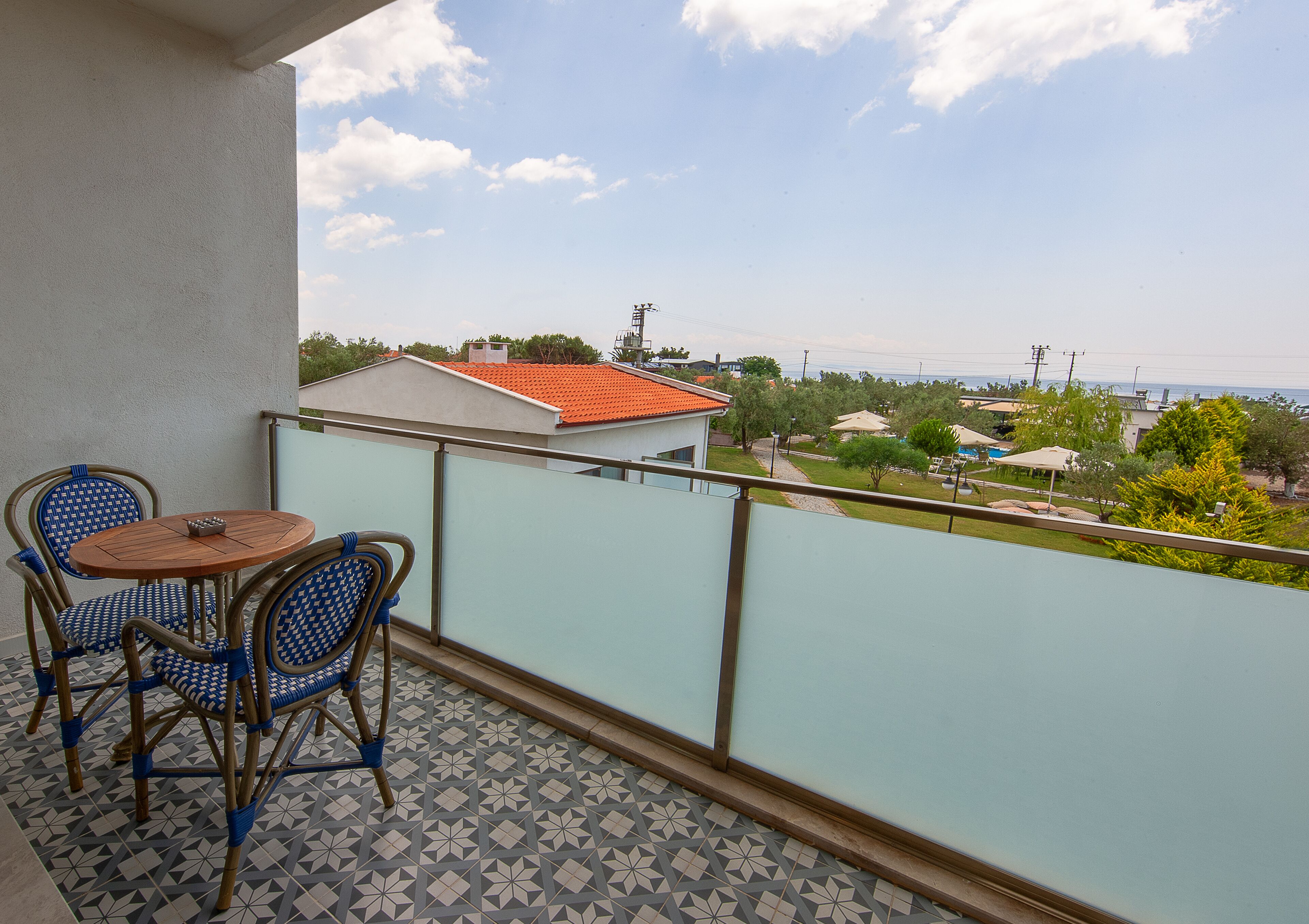A balcony with a tiled floor, two wicker chairs, and a small round table.