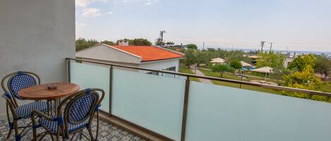 A balcony with a tiled floor, two wicker chairs, and a small round table.