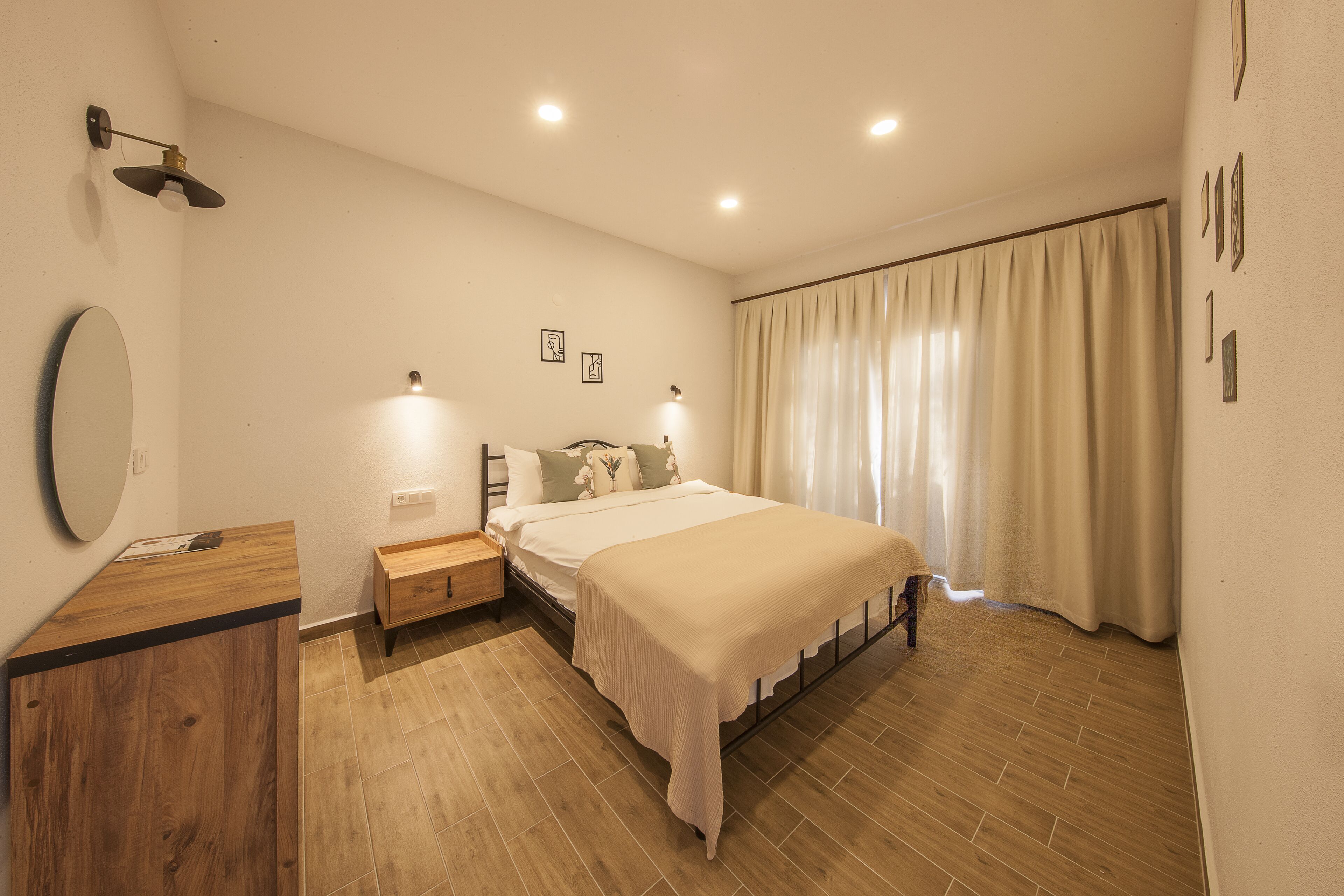 Un dormitorio con cama, mesitas de noche, un espejo y suelo de madera.