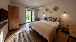 Quarto com uma cama grande, guarda-roupa de madeira, televisão e porta de vidro deslizante para o exterior.