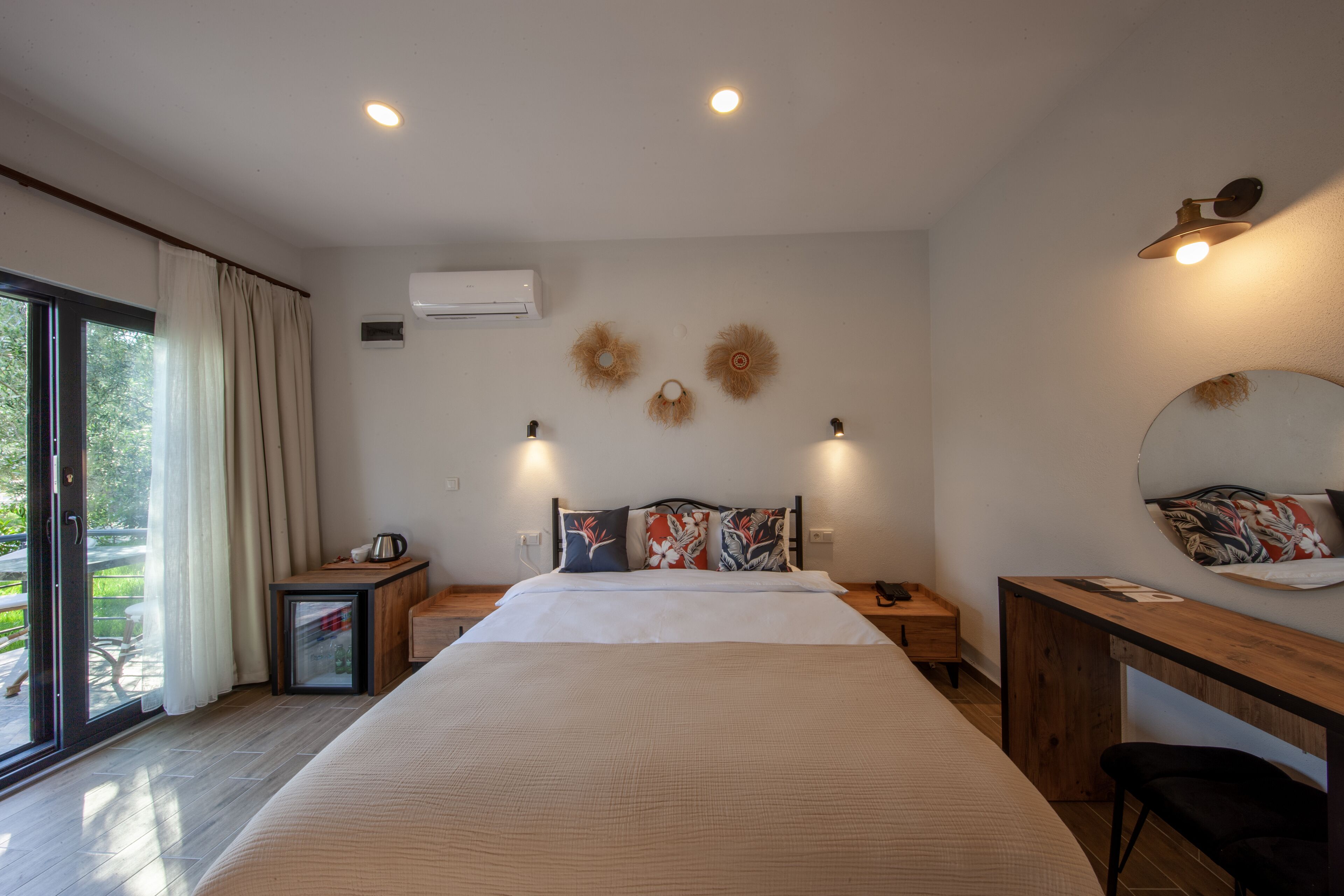 A modern bedroom with a large bed, bedside tables, a desk, and a view of the outdoors.
