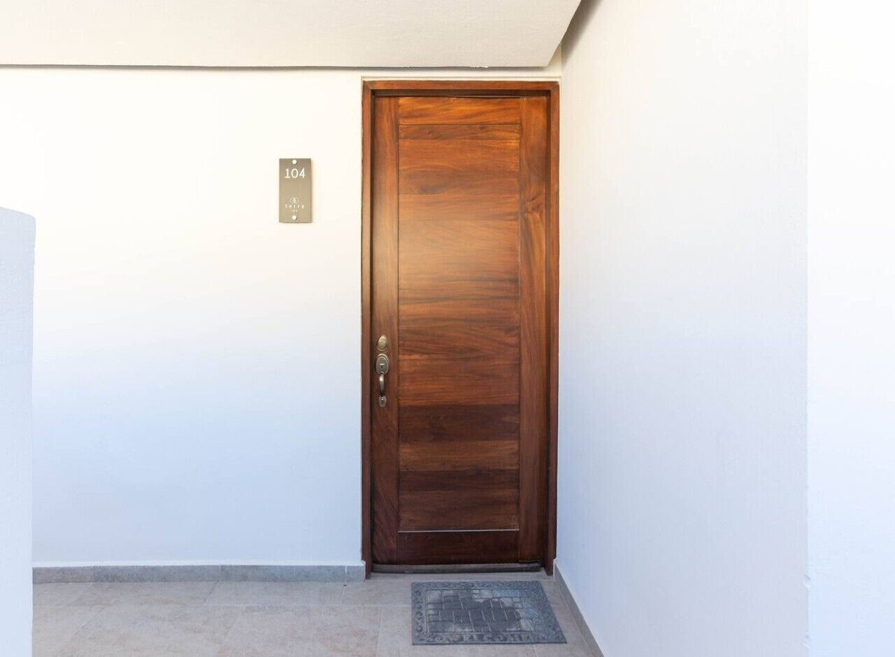 Une porte en bois fermée, dotée d’une poignée en laiton et d’une plaque numérotée au-dessus.