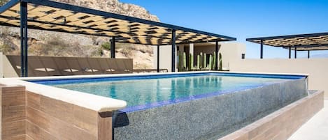 A rectangular swimming pool with a tiled edge, surrounded by a tiled deck area.