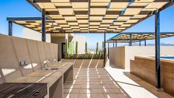 An outdoor patio with a built-in barbecue grill, a sink, and a pool area.