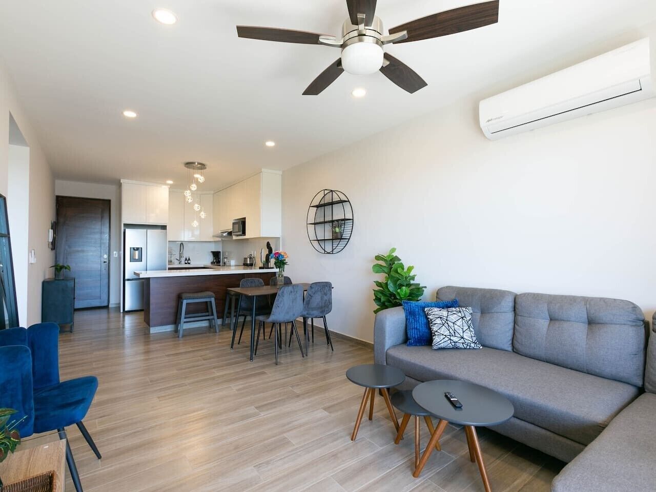A modern living room with a grey sofa, two round tables, and a ceiling fan.