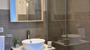 Un baño moderno con un espejo grande, tocador y cabina de ducha de vidrio.