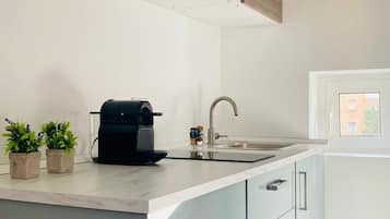 Una cucina moderna con forno a microonde integrato, macchina del caffè e lavello.