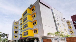 Un edificio residencial de varios pisos con diseño moderno, que cuenta con balcones y una combinación de colores amarillo y blanco en su fachada.