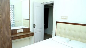 Una habitación de hotel con una cama, un aparador de madera, un espejo y una puerta que da a otra habitación.