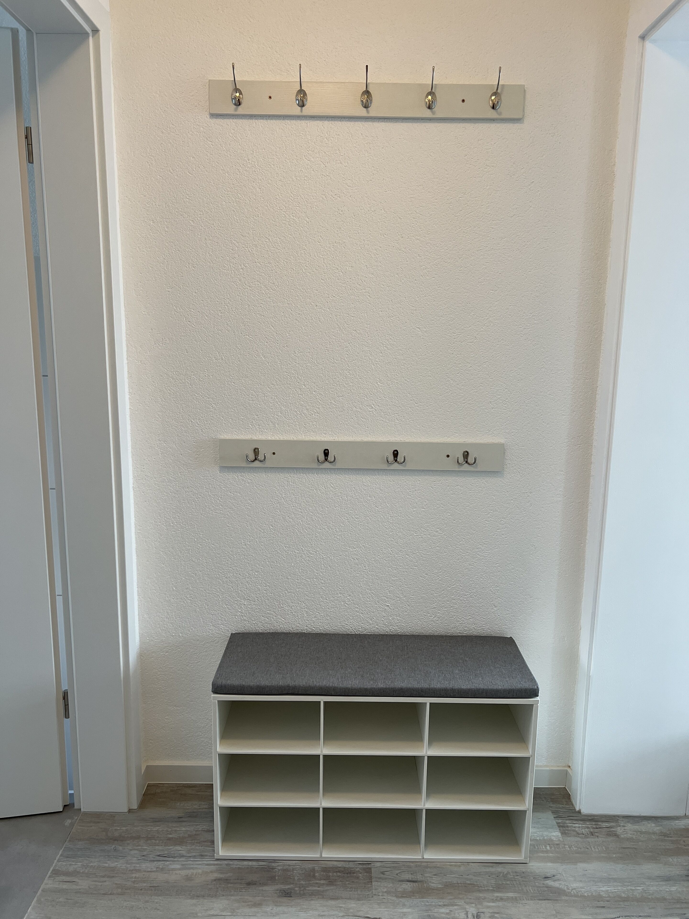 Un depósito con estanterías y ganchos en la pared, un banco con espacios de almacenamiento y una puerta a la izquierda.
