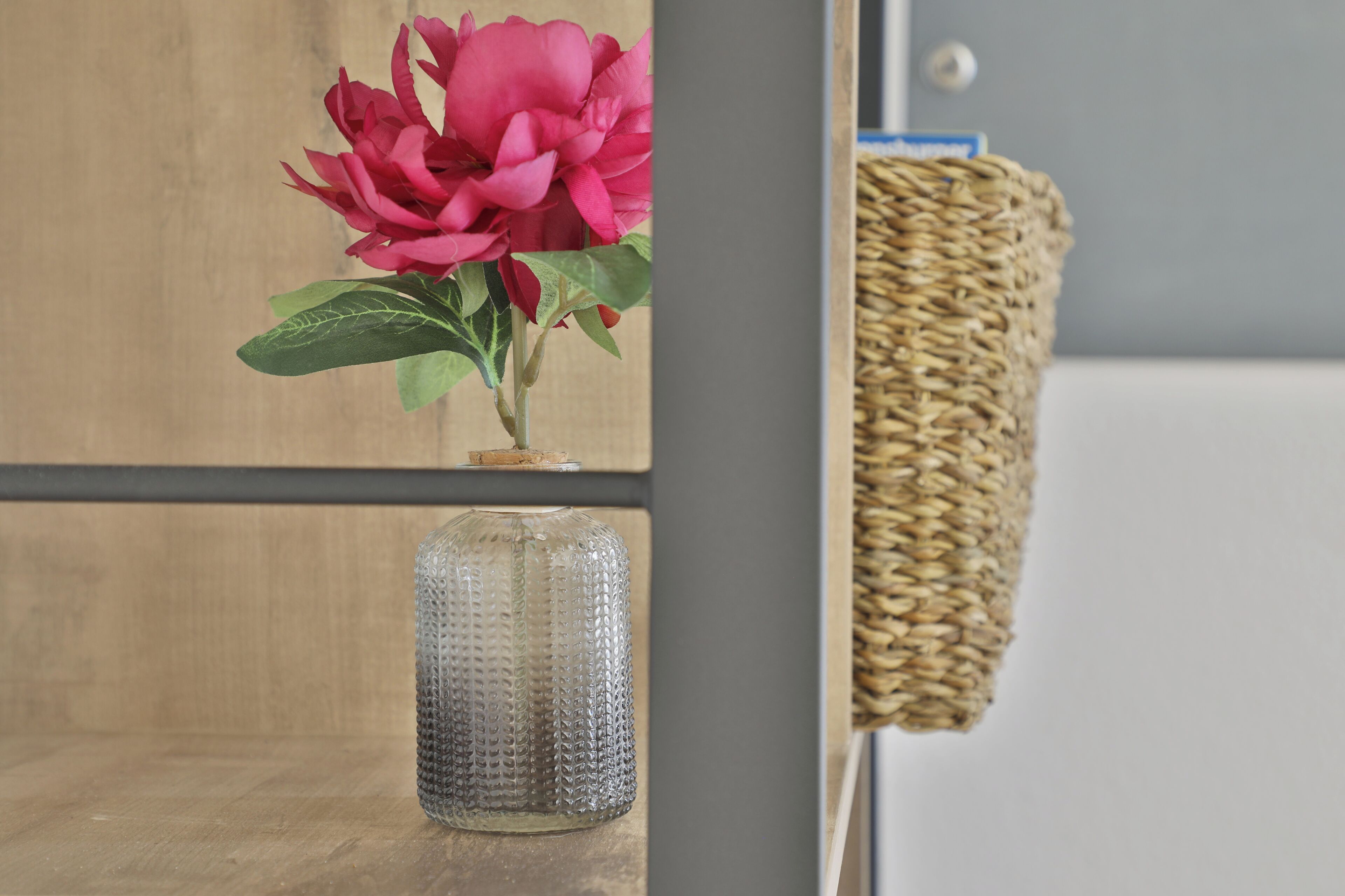A wooden shelf with a glass vase and a woven basket.