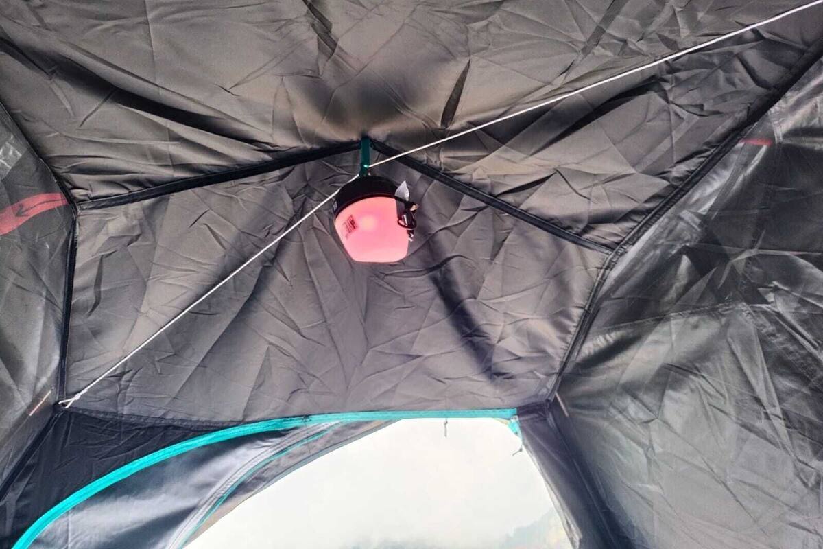 A tent with a central pole and a pink object hanging from it.