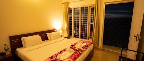 Ein Hotelzimmer mit Bett, Nachttisch, Sessel und Blick ins Freie.