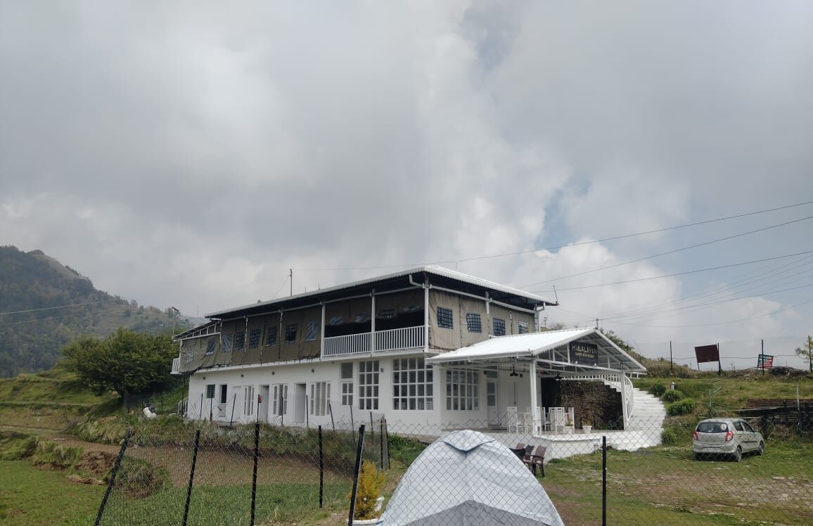 A two-story building with a balcony and a covered porch.