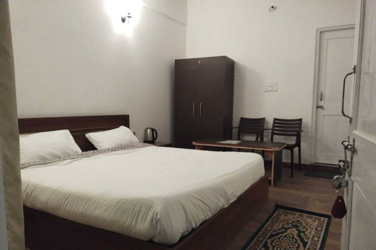 A bedroom with a bed, a wardrobe, a table, and two chairs.