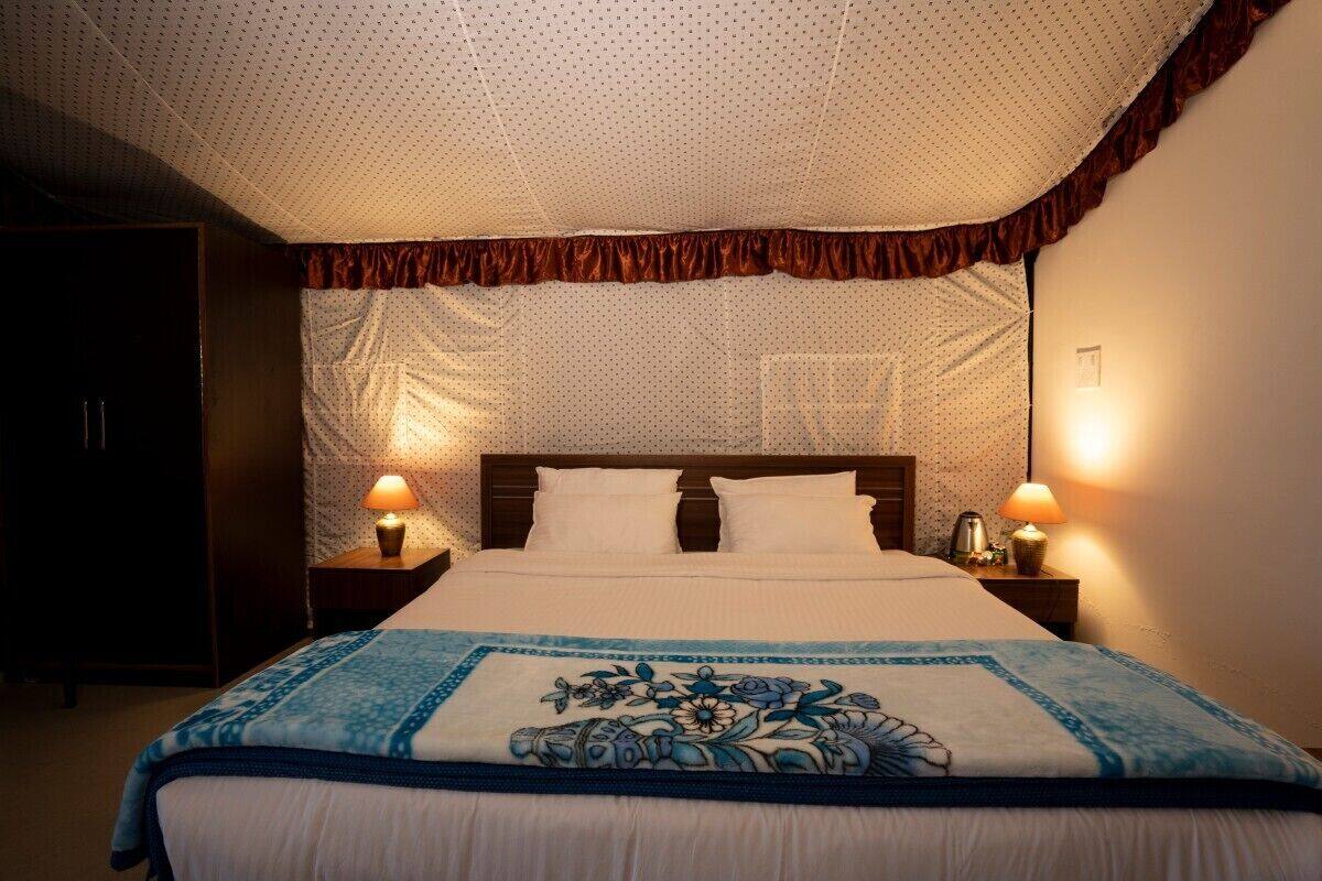 A neatly made bed with a floral-patterned blanket, two bedside lamps, and a polka-dotted ceiling.