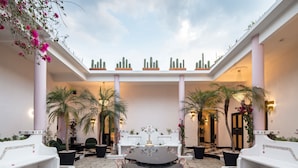 A spacious courtyard with a central round table, white benches, and potted plants. - HOLT’s Casa De Mi Independencia (Oaxaca de Juárez)