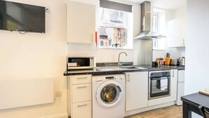 A compact kitchen with a washing machine, microwave, oven, and a sink.