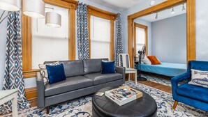 A modern living room with a grey sofa, blue armchair, and a coffee table. - The Dubuque House - Historic Downtown Location (Dubuque)