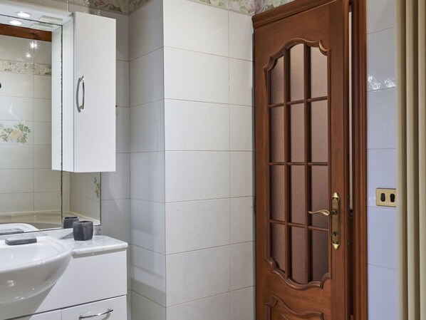A bathroom with a white sink, a mirror, and a wooden door with glass panels.