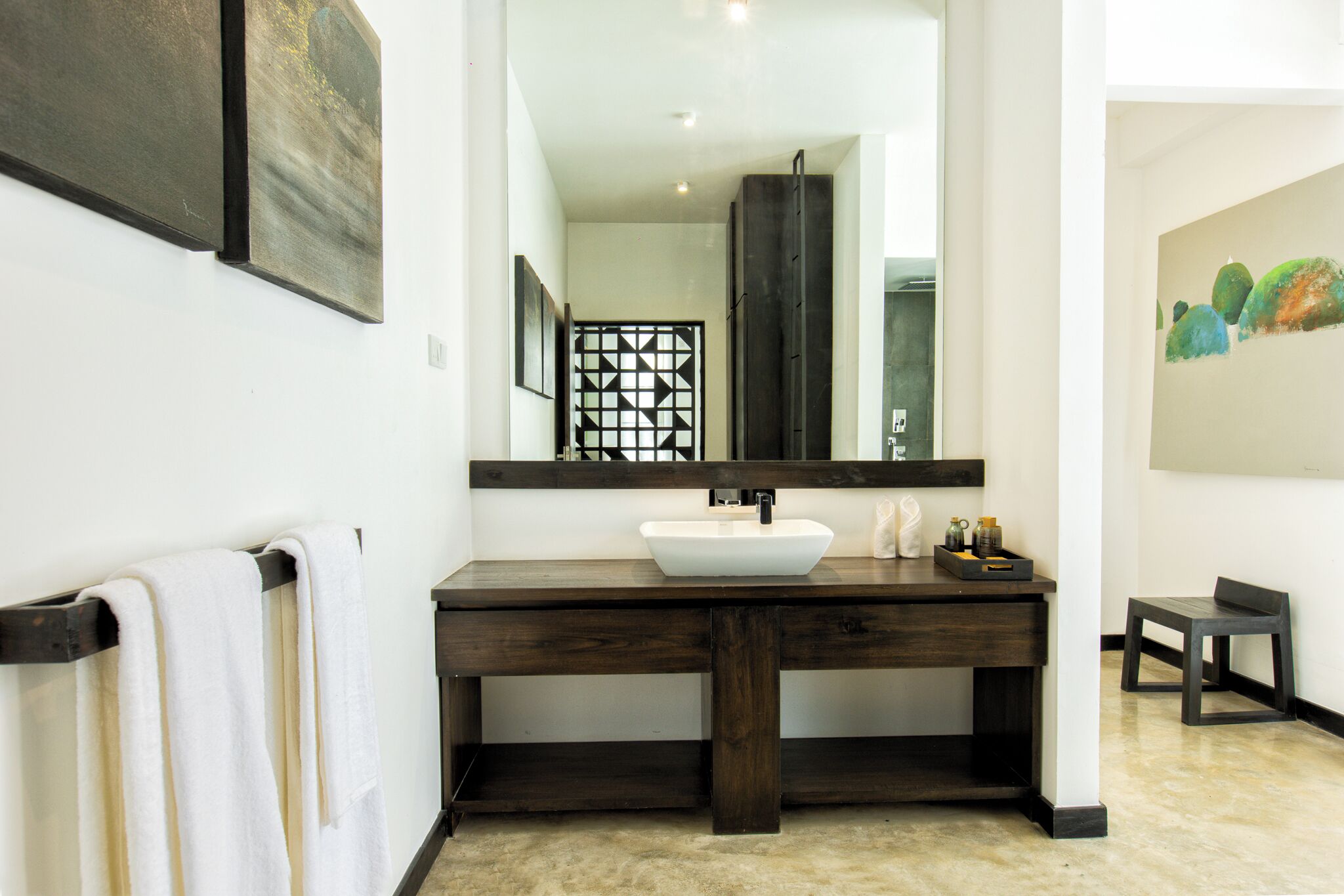 A bathroom with a wooden vanity, a white sink, and a large mirror.