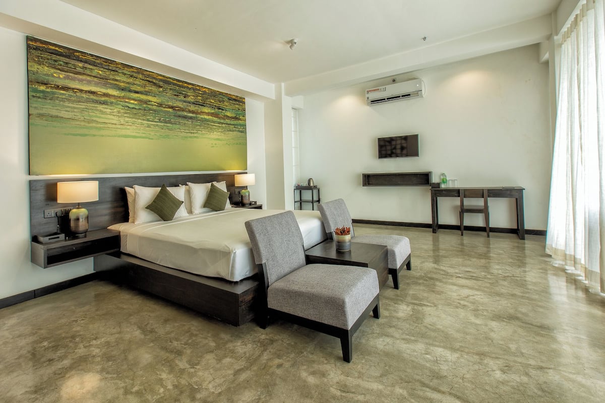 A modern hotel room with a large bed, a seating area, and a desk.