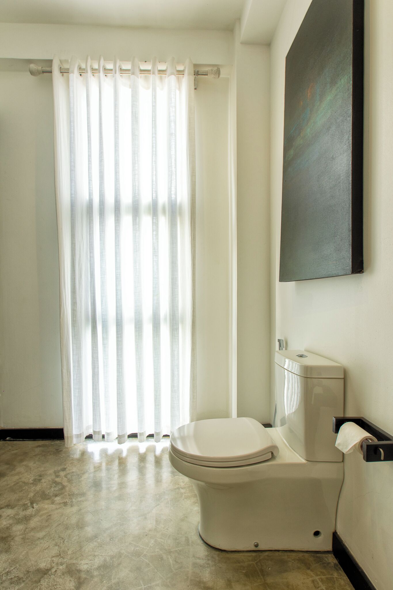 A bathroom with a toilet, a shower curtain, and a wall-mounted sink.
