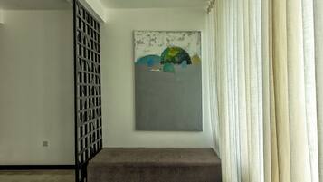 Una habitació amb un quadre abstracte gris a la paret, una partició metàl·lica negra i una banca gris.
