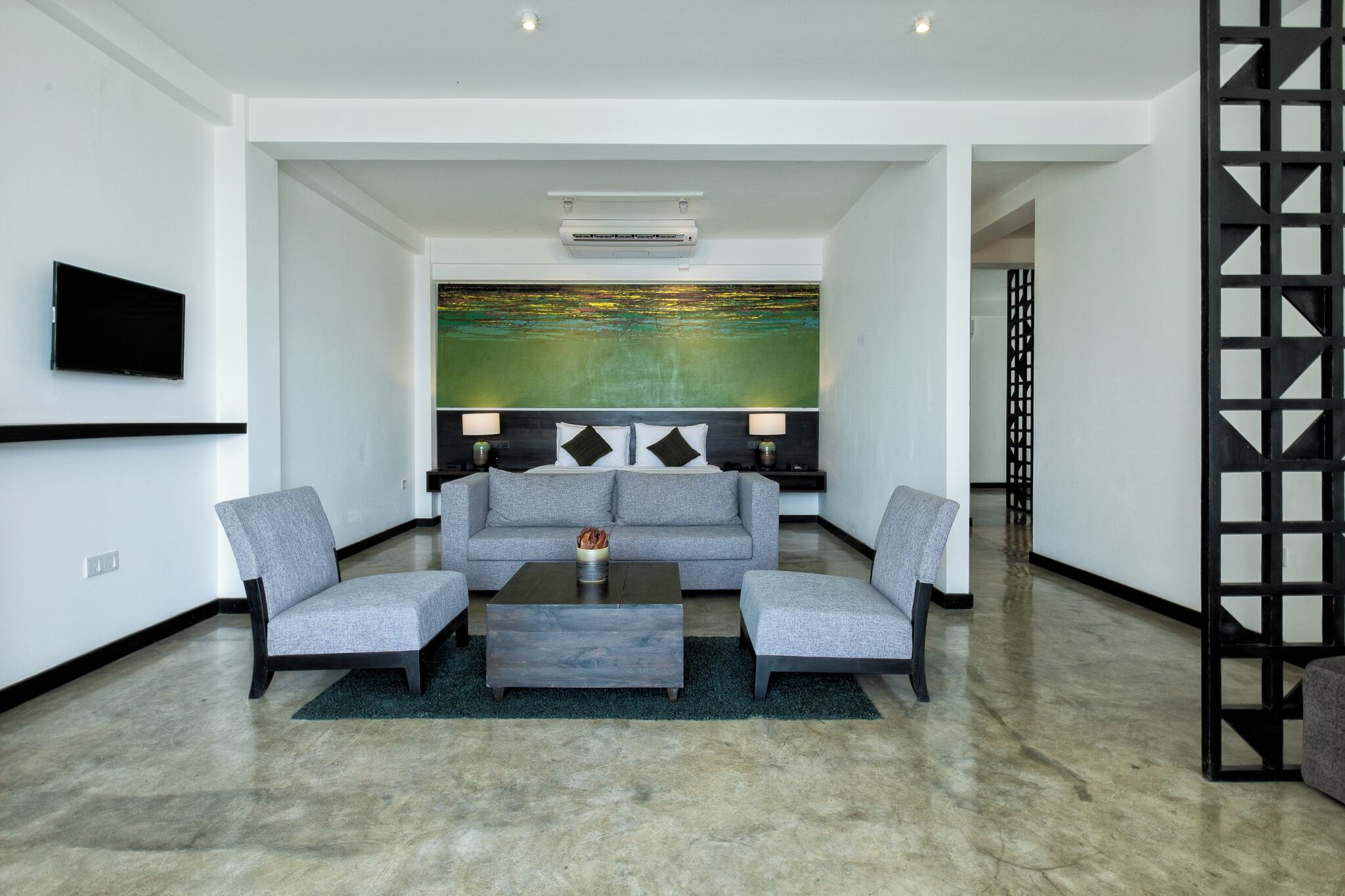 A modern living room with a grey sofa, two armchairs, a coffee table, and a large abstract painting on the wall.