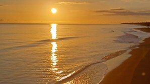 A beach at sunset with the sun reflecting on the water. - Nora's Flats - Trilo Apartament (Triscina)