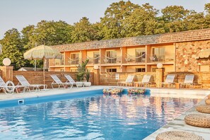 Zona de piscina con sillas de descanso y un edificio de madera con balcones.