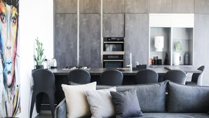 A modern living room with a grey sofa, a dining area with a dark wooden table, and a kitchen with built-in appliances. - YalaRent Midtown towers TLV (Tel Aviv)