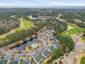 An aerial view of a residential area with houses, a swimming pool, and a lake.