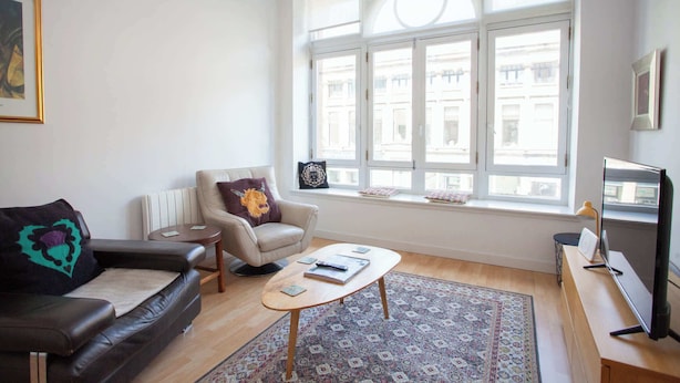 Un salon comprenant un canapé, un fauteuil, une table basse et un téléviseur.