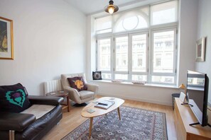 Ein Wohnzimmer mit Sofa, Sessel, Couchtisch und Fernseher.