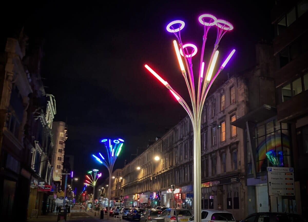 Une rue bordée d’immeubles et illuminée de lumières colorées.