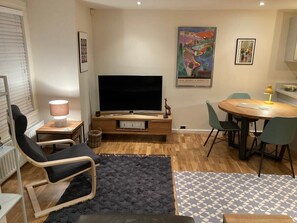 Un salon avec un téléviseur, une table à manger et des chaises.