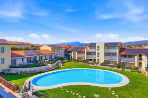 Un resort con piscina, edificios de varios pisos y montañas al fondo.