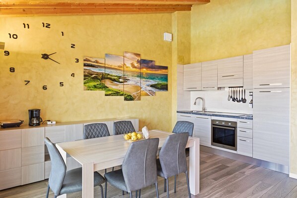 Una cocina moderna con techo de madera, una zona de comedor con mesa y sillas, y un reloj de pared.