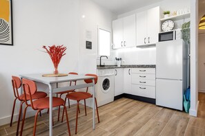 A modern kitchen with white cabinets, a washing machine, a microwave, and a dining area with a table and chairs. - Apartment "The Sunset Calafell" near the beach with Wi-Fi (Vendrell)