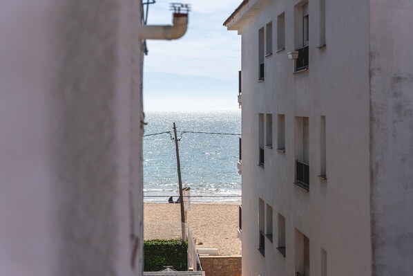 Vista de una playa desde un edificio con varias ventanas y una línea eléctrica visible.
