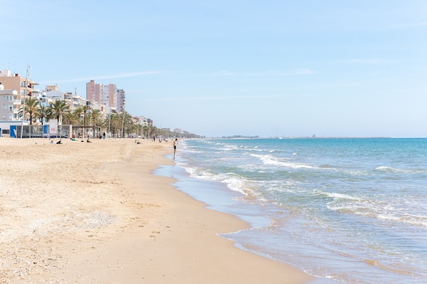 A beach with a sandy shore, palm trees, and buildings in the background. - Apartment "The Sunset Calafell" near the beach with Wi-Fi (Vendrell)