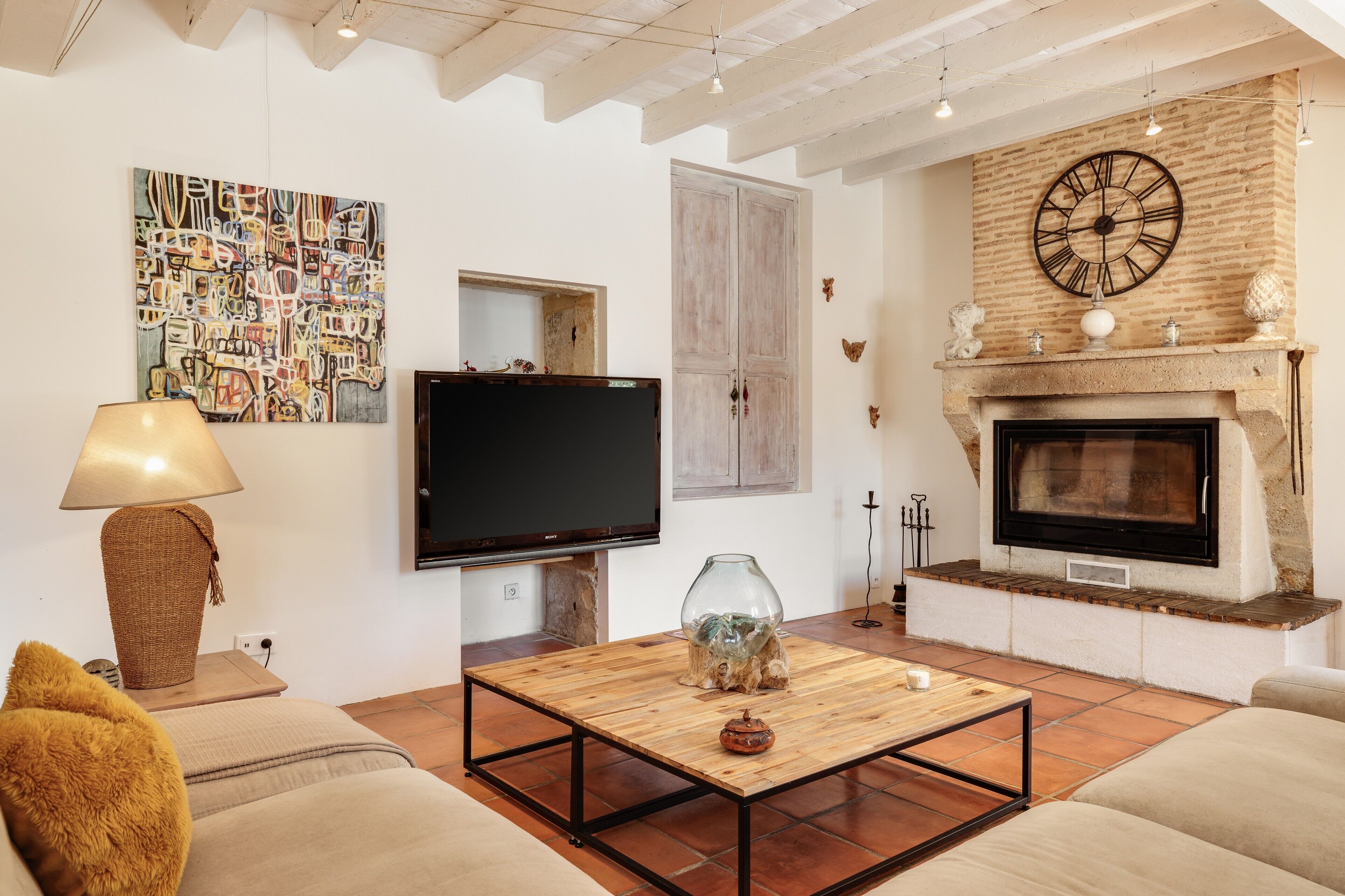 A living room with a television, fireplace, and a painting on the wall.