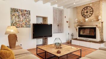 A living room with a television, fireplace, and a painting on the wall.