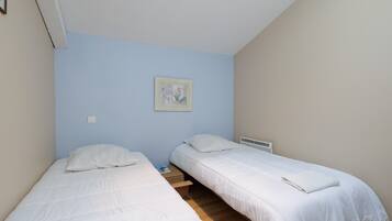 A bedroom with two single beds, a small bedside table, a wall-mounted picture, and a radiator.