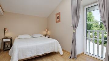 Un dormitorio con cama, mesitas de noche, una ventana con cortinas y vistas al exterior.