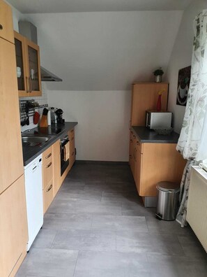 A compact kitchen with wooden cabinets, a built-in oven, and a small trash bin. - Apartment in Klagenfurt (Sankt Peter am Bichl)