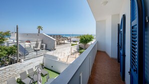 Ein Balkon mit Meerblick, ein Fliesenboden und eine blaue Tür.